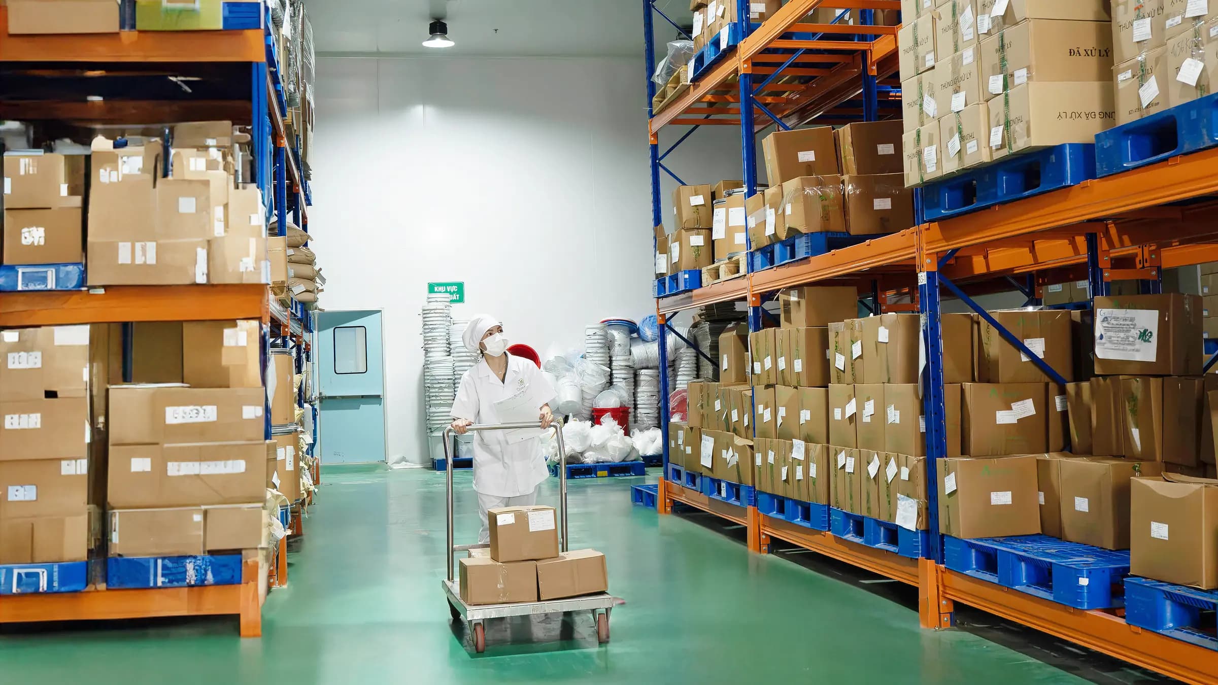 Khu vực lưu trữ có nhiều thùng hàng, nhân viên đẩy xe hàng